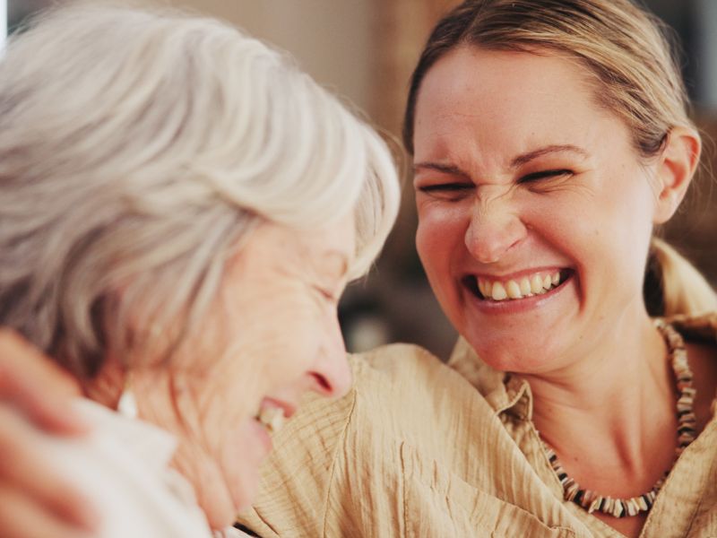An adult and her senior mother smile at one another when considering assisted senior living options.