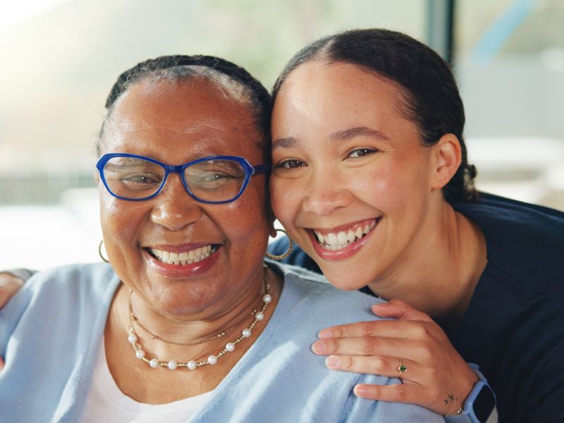 An adult daughter smiles for the camera with her aging parent at a certified dementia care facility in Wisconsin